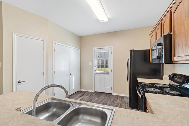 kitchen featuring sink, dark wood-type flooring, and black appliances