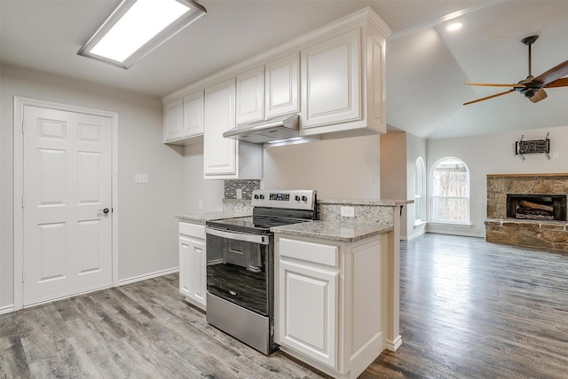 kitchen with a stone fireplace, electric range, ceiling fan, light wood-type flooring, and white cabinetry