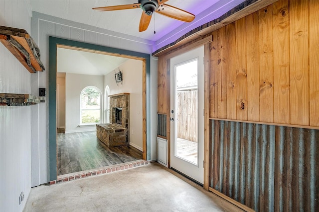 doorway to outside with a stone fireplace and ceiling fan