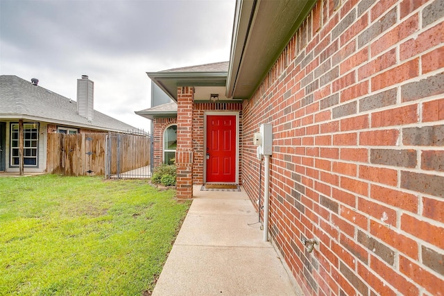 view of exterior entry featuring a lawn