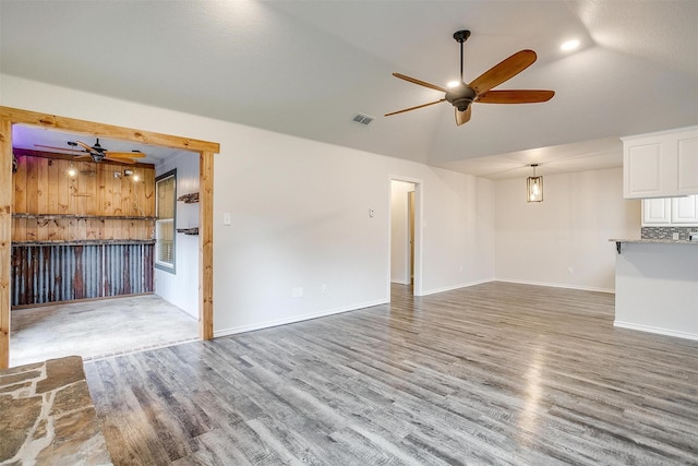 unfurnished living room featuring a textured ceiling, hardwood / wood-style flooring, vaulted ceiling, and ceiling fan