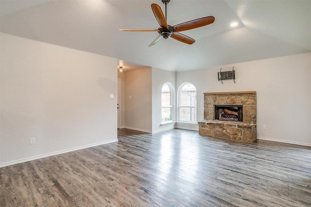 unfurnished living room with ceiling fan, a stone fireplace, wood-type flooring, and vaulted ceiling