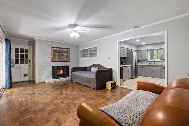 living room with ceiling fan, sink, parquet flooring, crown molding, and a fireplace