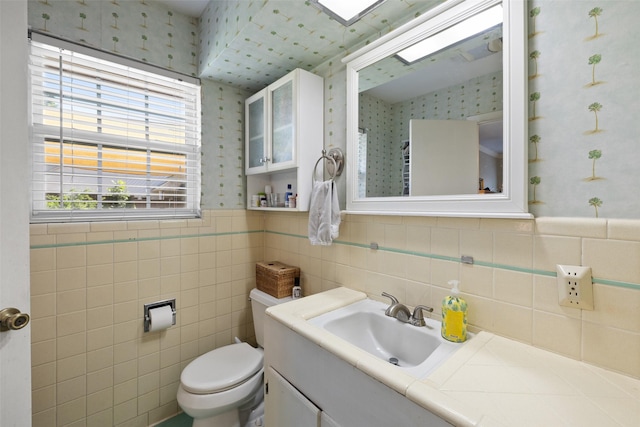 bathroom featuring vanity, toilet, and tile walls