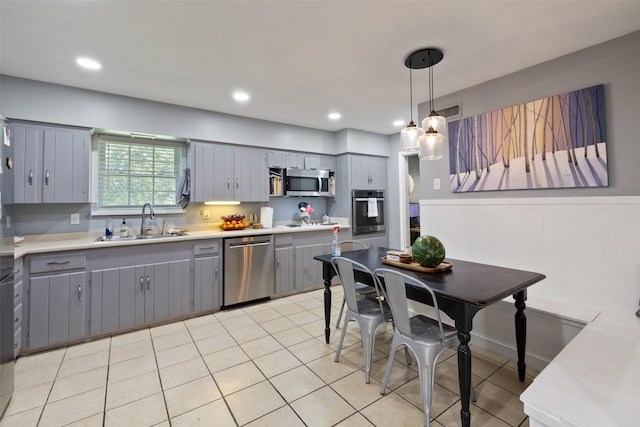 kitchen featuring appliances with stainless steel finishes, decorative light fixtures, gray cabinets, and sink