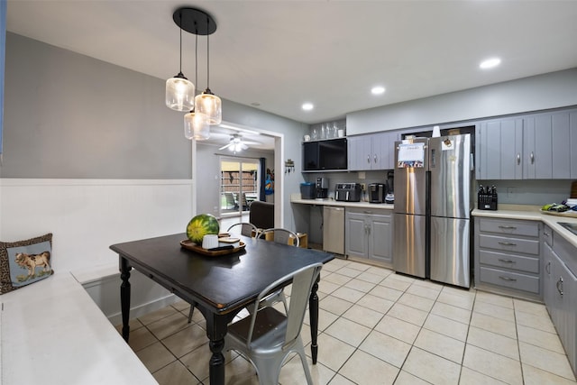 kitchen with gray cabinetry, stainless steel appliances, ceiling fan, hanging light fixtures, and light tile patterned flooring