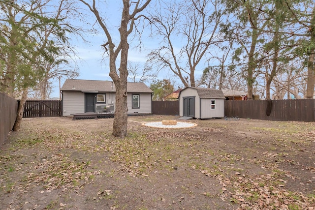 back of house with a shed and an outdoor fire pit