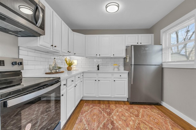 kitchen featuring sink, white cabinets, stainless steel appliances, and light wood-type flooring