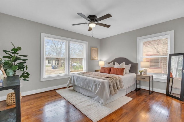 bedroom with multiple windows, dark hardwood / wood-style floors, and ceiling fan