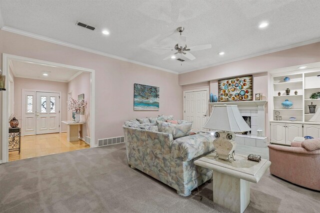 living room featuring ornamental molding, a textured ceiling, and a tile fireplace