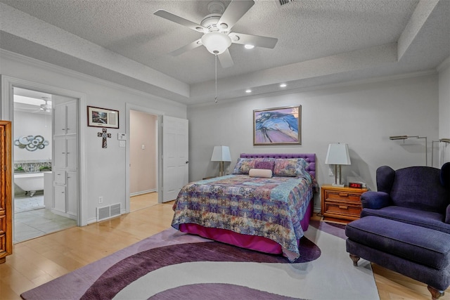 bedroom featuring ceiling fan, light hardwood / wood-style flooring, crown molding, a textured ceiling, and a tray ceiling