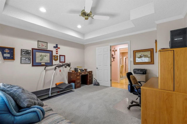 carpeted office space with a textured ceiling, a tray ceiling, ceiling fan, and ornamental molding