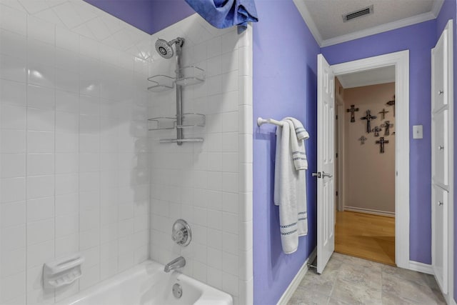 bathroom featuring crown molding, a textured ceiling, and tiled shower / bath