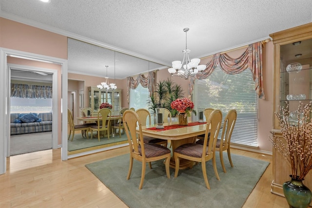 dining room featuring crown molding, light wood-type flooring, a textured ceiling, and a notable chandelier