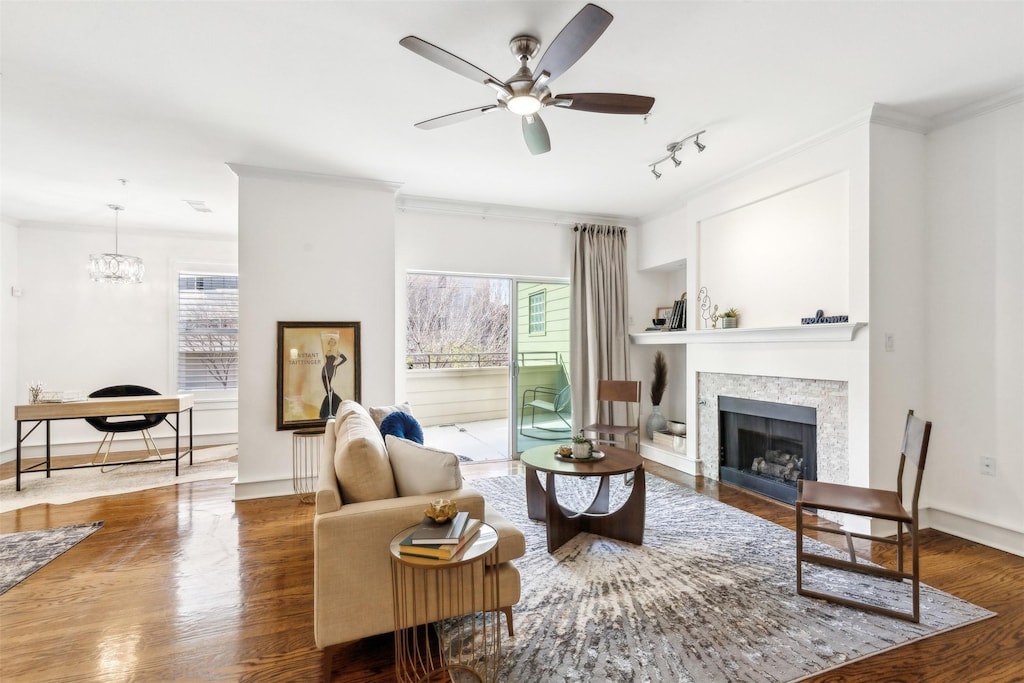 living room featuring hardwood / wood-style flooring, ornamental molding, and ceiling fan with notable chandelier