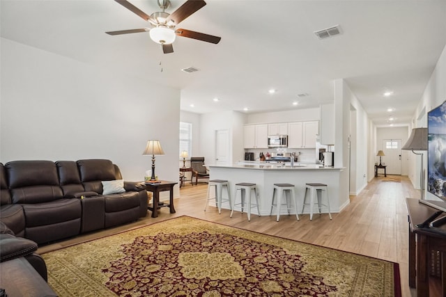 living room with light hardwood / wood-style flooring, ceiling fan, and sink