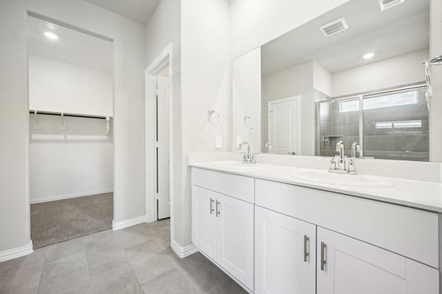 full bathroom with a stall shower, a walk in closet, visible vents, and a sink