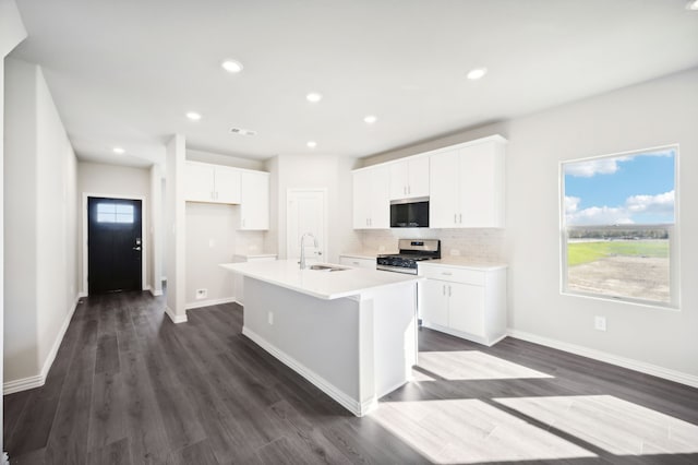 kitchen featuring a center island with sink, stainless steel appliances, light countertops, white cabinetry, and a sink