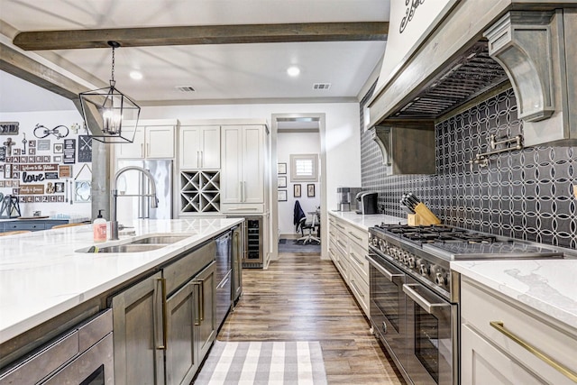 kitchen featuring beam ceiling, light stone countertops, sink, high end stainless steel range, and custom range hood