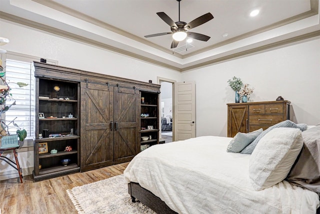 bedroom with a tray ceiling, ceiling fan, and light hardwood / wood-style flooring