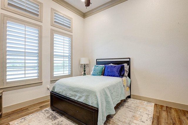 bedroom featuring ceiling fan, wood-type flooring, and ornamental molding