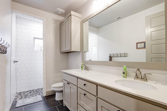 bathroom featuring tile patterned floors, vanity, toilet, and tiled shower