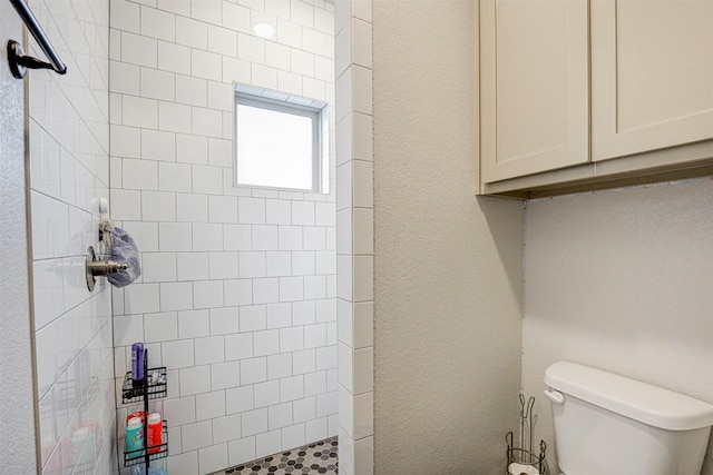 bathroom featuring a tile shower and toilet