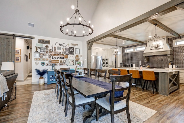 dining space with beam ceiling, a barn door, and dark wood-type flooring