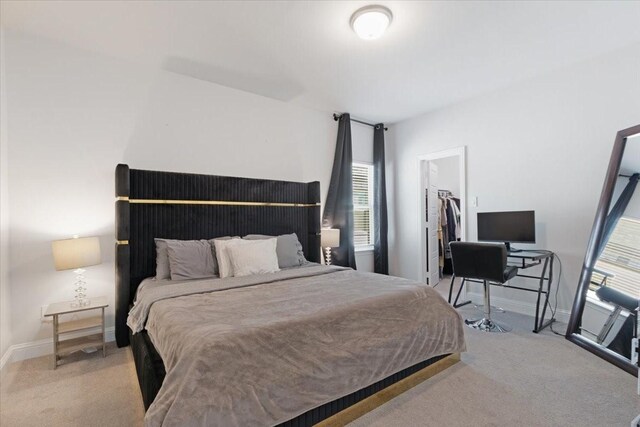 bedroom with a walk in closet, light carpet, and a closet