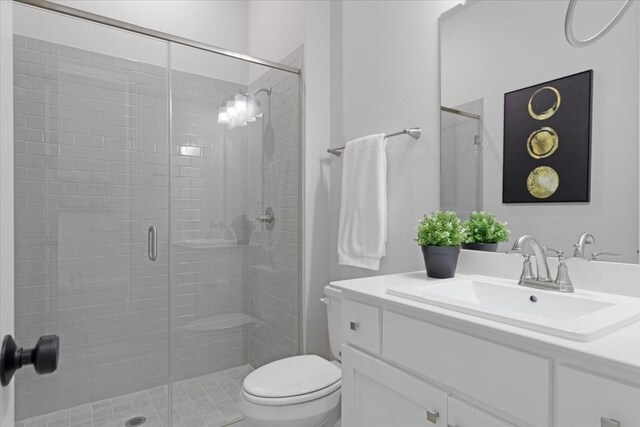 bathroom featuring vanity, toilet, and a shower with door