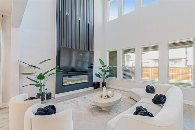 living room with hardwood / wood-style floors, a healthy amount of sunlight, and a towering ceiling