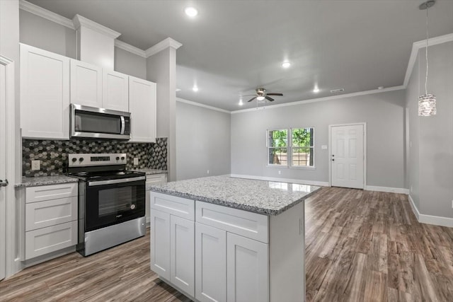 kitchen with tasteful backsplash, decorative light fixtures, white cabinets, and appliances with stainless steel finishes