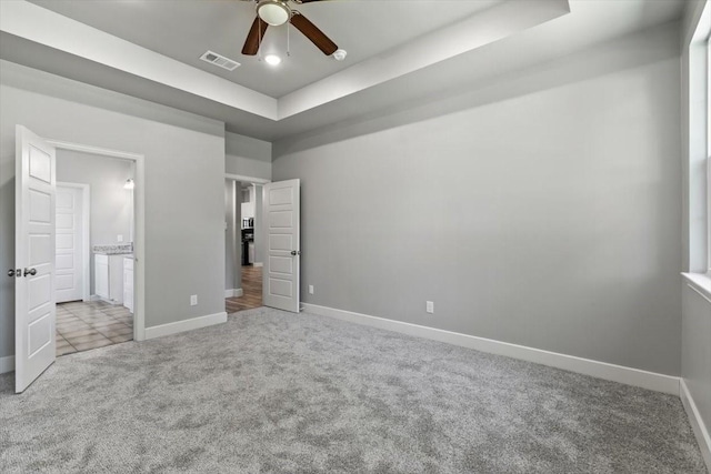 unfurnished bedroom with a tray ceiling, ceiling fan, and light carpet