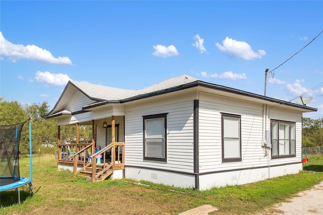 exterior space with a yard, covered porch, and a trampoline