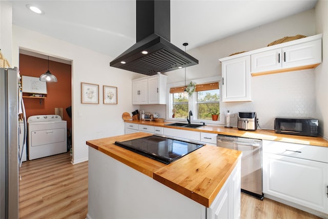 kitchen with wood counters, island exhaust hood, black appliances, decorative light fixtures, and washer / clothes dryer