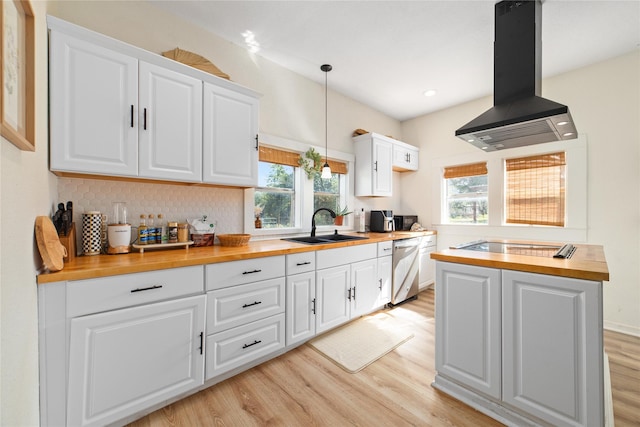 kitchen with island exhaust hood, sink, decorative light fixtures, white cabinets, and butcher block countertops