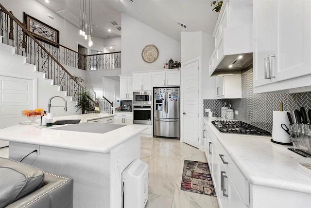 kitchen featuring appliances with stainless steel finishes, a kitchen island with sink, and white cabinets