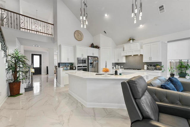 kitchen with pendant lighting, white cabinetry, stainless steel appliances, and a center island with sink