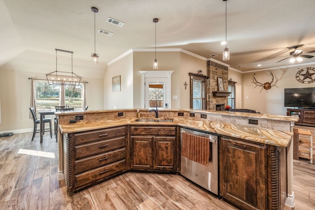 kitchen featuring a center island with sink, dishwasher, sink, and decorative light fixtures