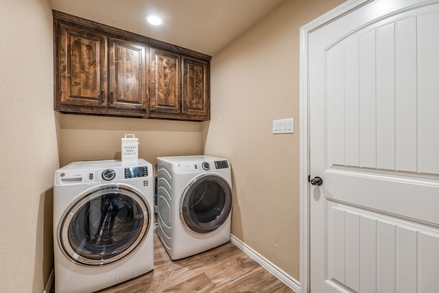 laundry area with cabinets, light wood-type flooring, and washing machine and clothes dryer