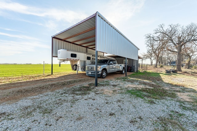 view of vehicle parking featuring a rural view and a carport