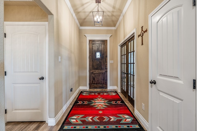 doorway to outside with a chandelier, hardwood / wood-style flooring, and crown molding