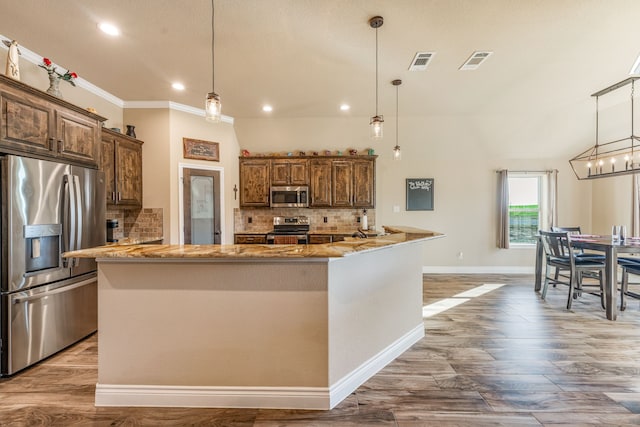 kitchen with kitchen peninsula, pendant lighting, and stainless steel appliances