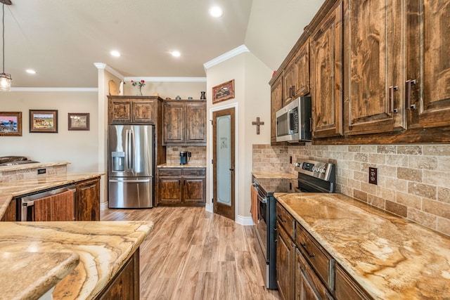 kitchen featuring stainless steel appliances, backsplash, crown molding, pendant lighting, and light wood-type flooring