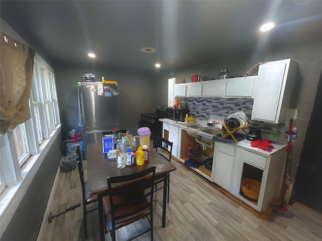 kitchen with tasteful backsplash, white cabinetry, fridge, and light hardwood / wood-style floors