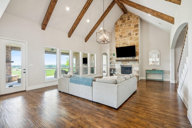 living room featuring high vaulted ceiling, a stone fireplace, dark hardwood / wood-style floors, beamed ceiling, and a notable chandelier