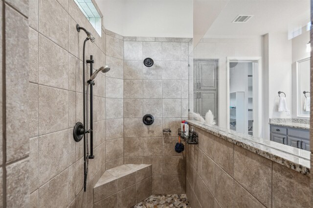 bathroom with a tile shower and vanity