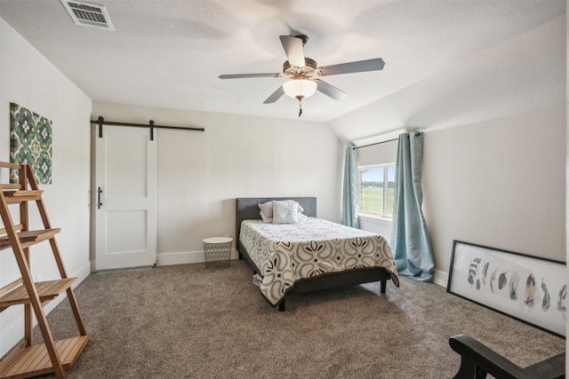 carpeted bedroom with ceiling fan, a barn door, and vaulted ceiling