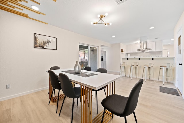 dining area with a notable chandelier and light hardwood / wood-style flooring