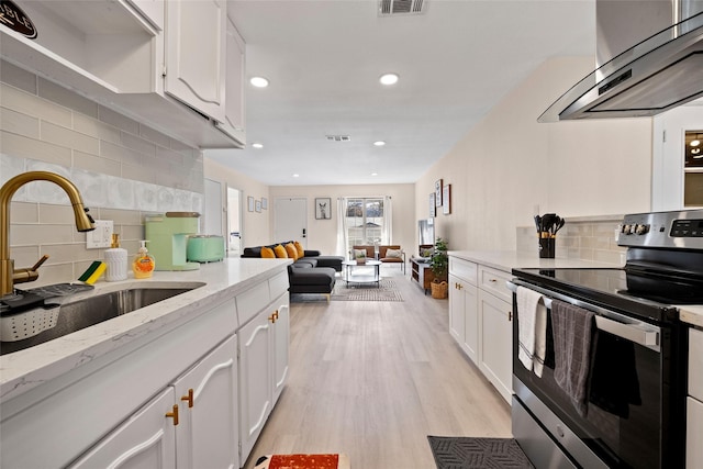 kitchen with stainless steel range with electric stovetop, white cabinetry, sink, and exhaust hood